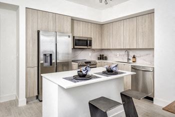 A kitchen with a white counter top and a stainless steel refrigerator